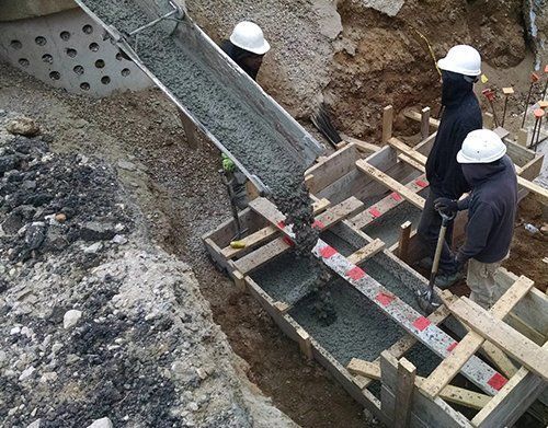 a group of construction workers are pouring concrete into a hole