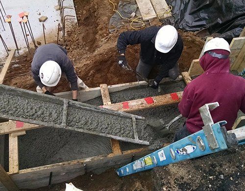a group of construction workers are pouring concrete into a hole