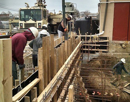 a group of construction workers are working on a concrete wall