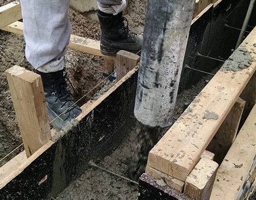 a person is pouring concrete into a wooden form