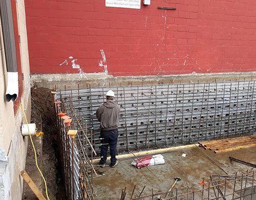 a man in a hard hat is standing in front of a brick wall