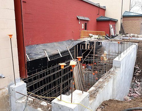 a concrete wall is being built in front of a red building