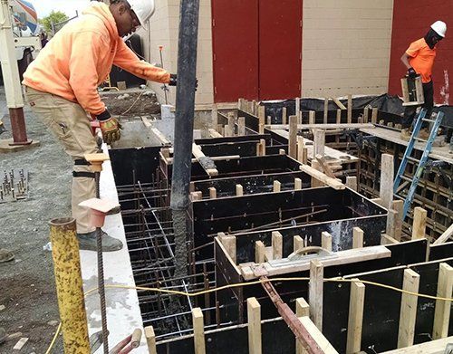 a man is pouring concrete into a hole in a construction site
