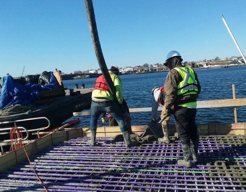 a group of construction workers are working on a bridge over a body of water