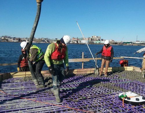 a group of construction workers are working on a bridge over a body of water