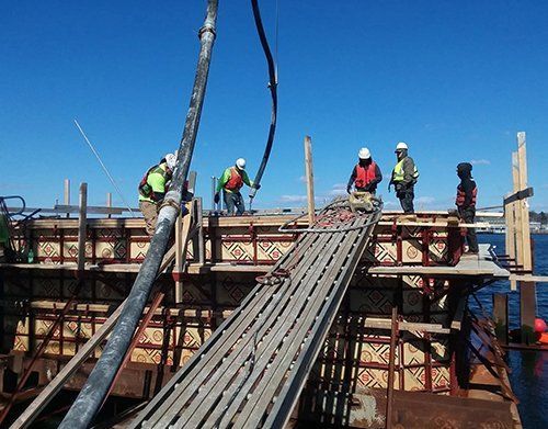 a group of construction workers are working on a bridge over a body of water