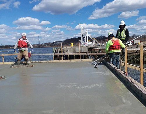a group of construction workers are working on a bridge over a body of water