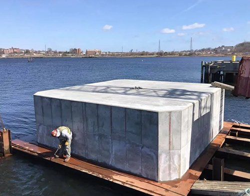 a man is standing on a dock next to a large concrete block in the water