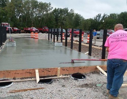 a man in a pink shirt is working on a concrete floor