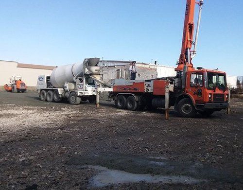 a concrete mixer truck is parked next to a concrete pump truck