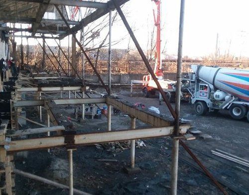 a concrete mixer truck is pouring concrete into a building under construction
