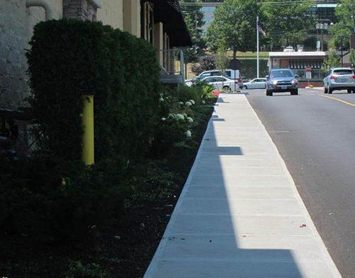 a sidewalk with a yellow pole on the side of it