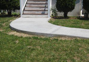 a concrete walkway leading to a set of stairs in a yard