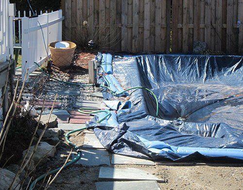 a blue tarp is covering a swimming pool in a backyard