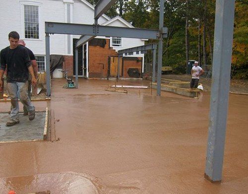a group of men are working on a concrete floor in front of a church