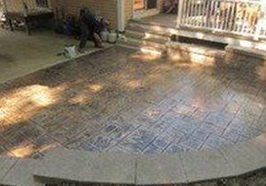 a person is standing on a concrete patio in front of a house