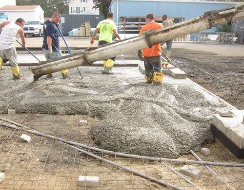 a group of construction workers are pouring concrete on the ground