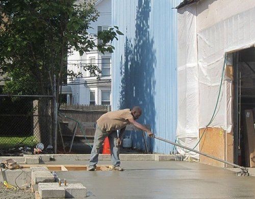a man is working on a concrete floor in front of a blue building