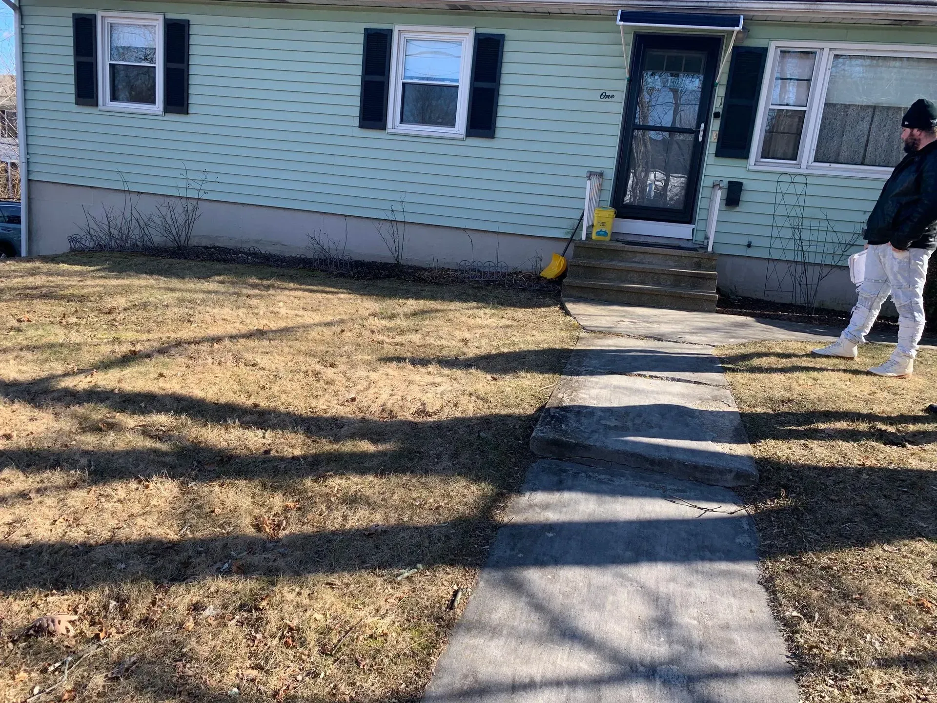 a man is walking down a sidewalk in front of a house
