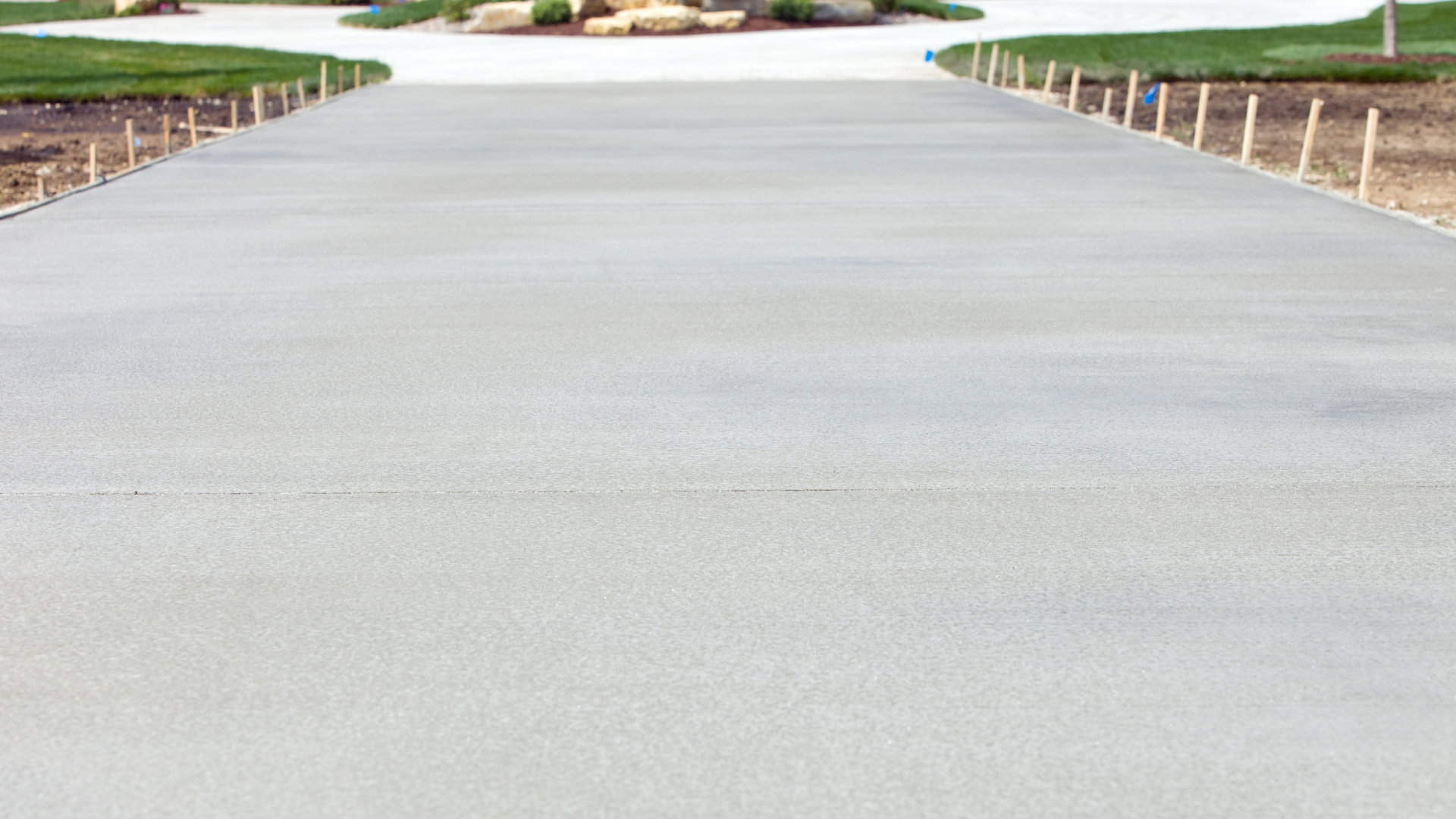 a concrete driveway leading to a house with grass on the side