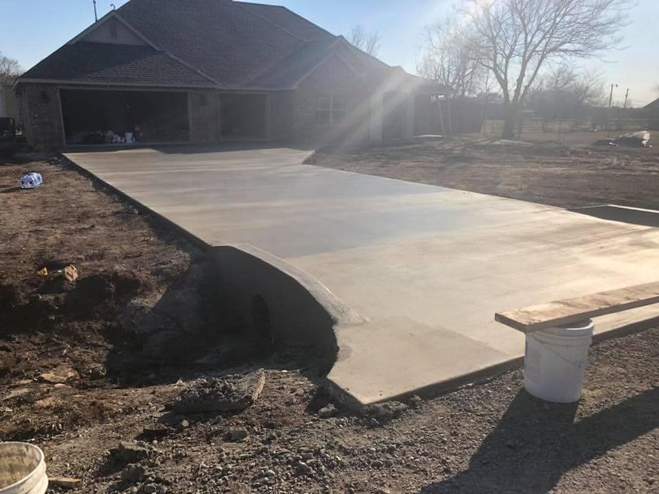 A large concrete driveway is being built in front of a house.