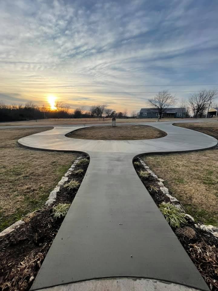 A concrete walkway leading to a house with a sunset in the background.