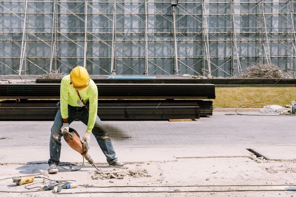 A Construction Worker Is Using A Hammer To Break A Concrete Slab — Pro Cut N Core In Mareeba, QLD