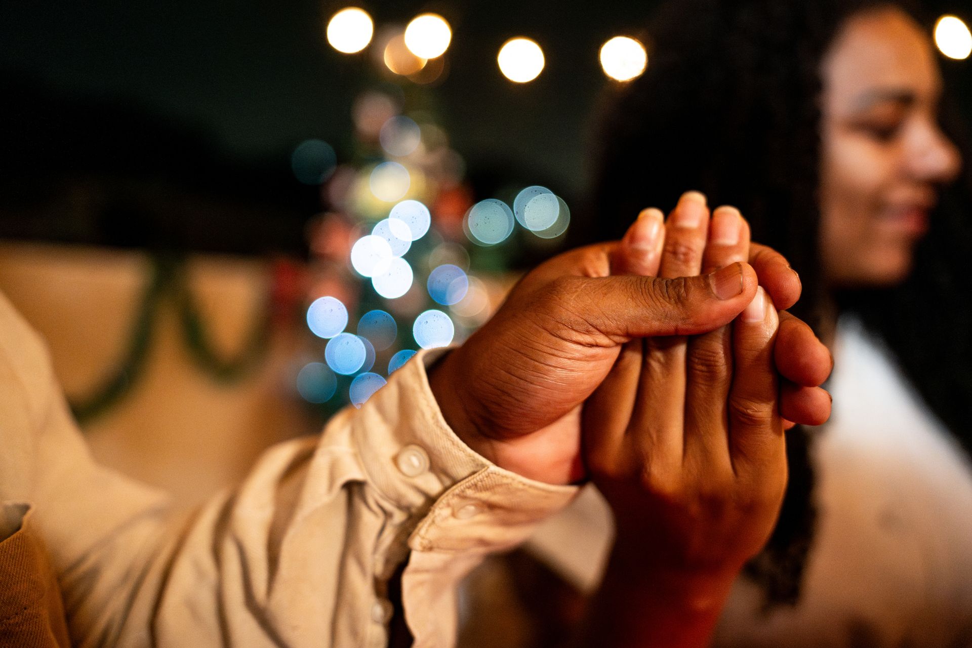 Two people holding hands, blurred lights in background.