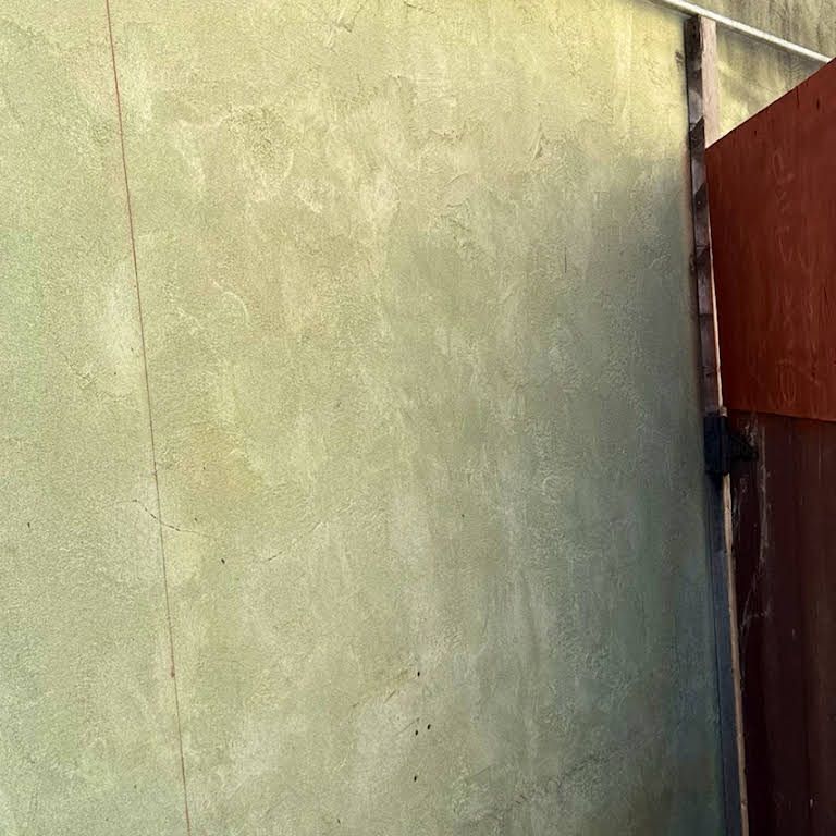 A close up of a wall with a door in the background