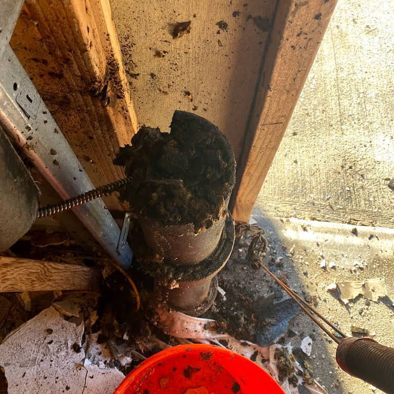 A person is cleaning a pipe with a hose and a bucket