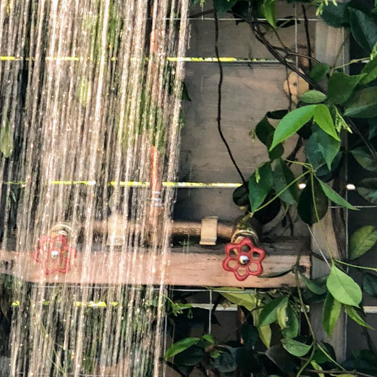 A close up of a shower with a red handle