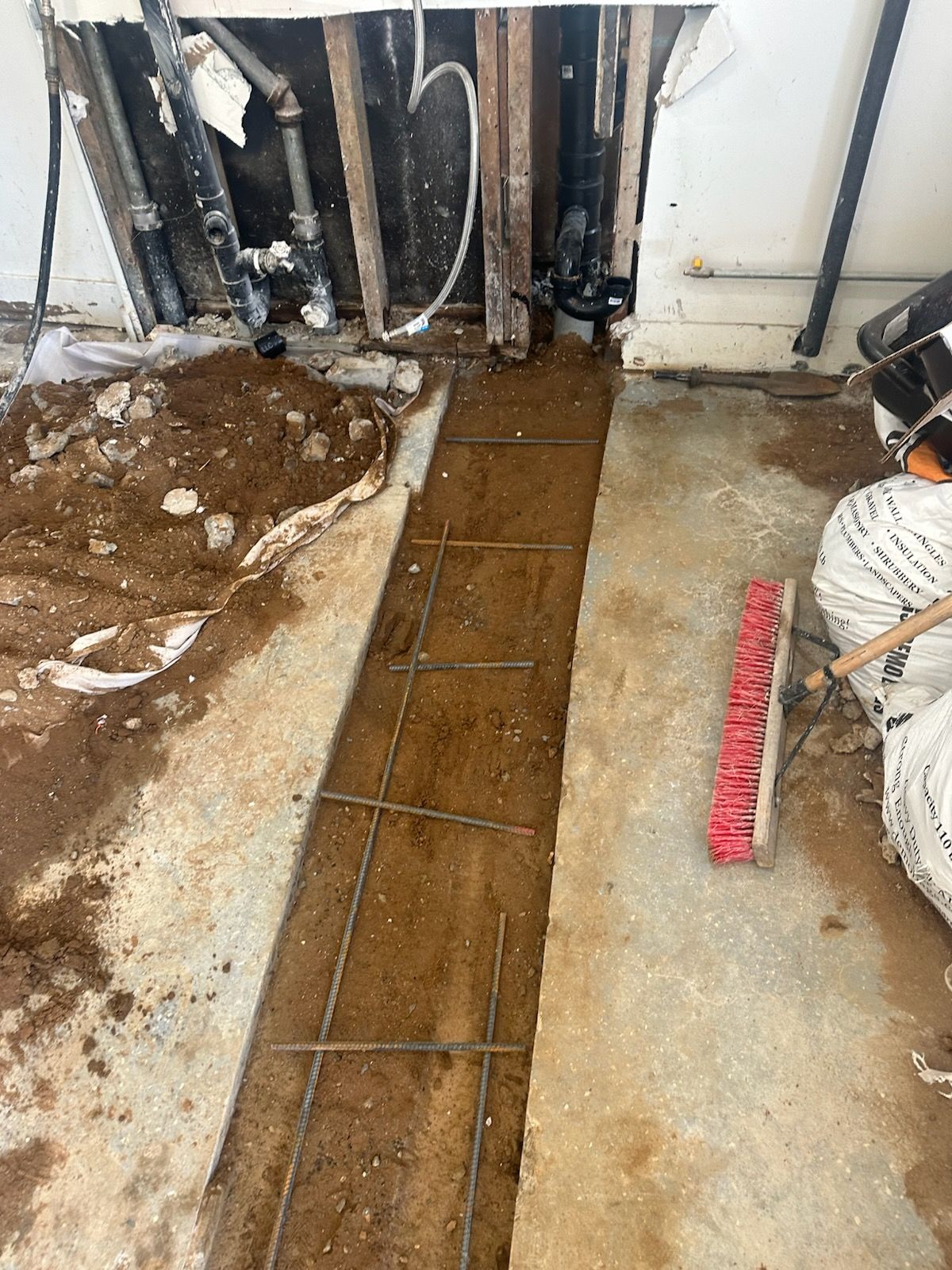 A person is laying concrete in a room with a broom.