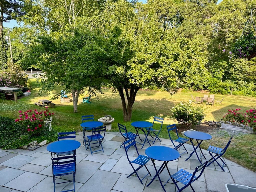 A patio with blue tables and chairs in a garden.