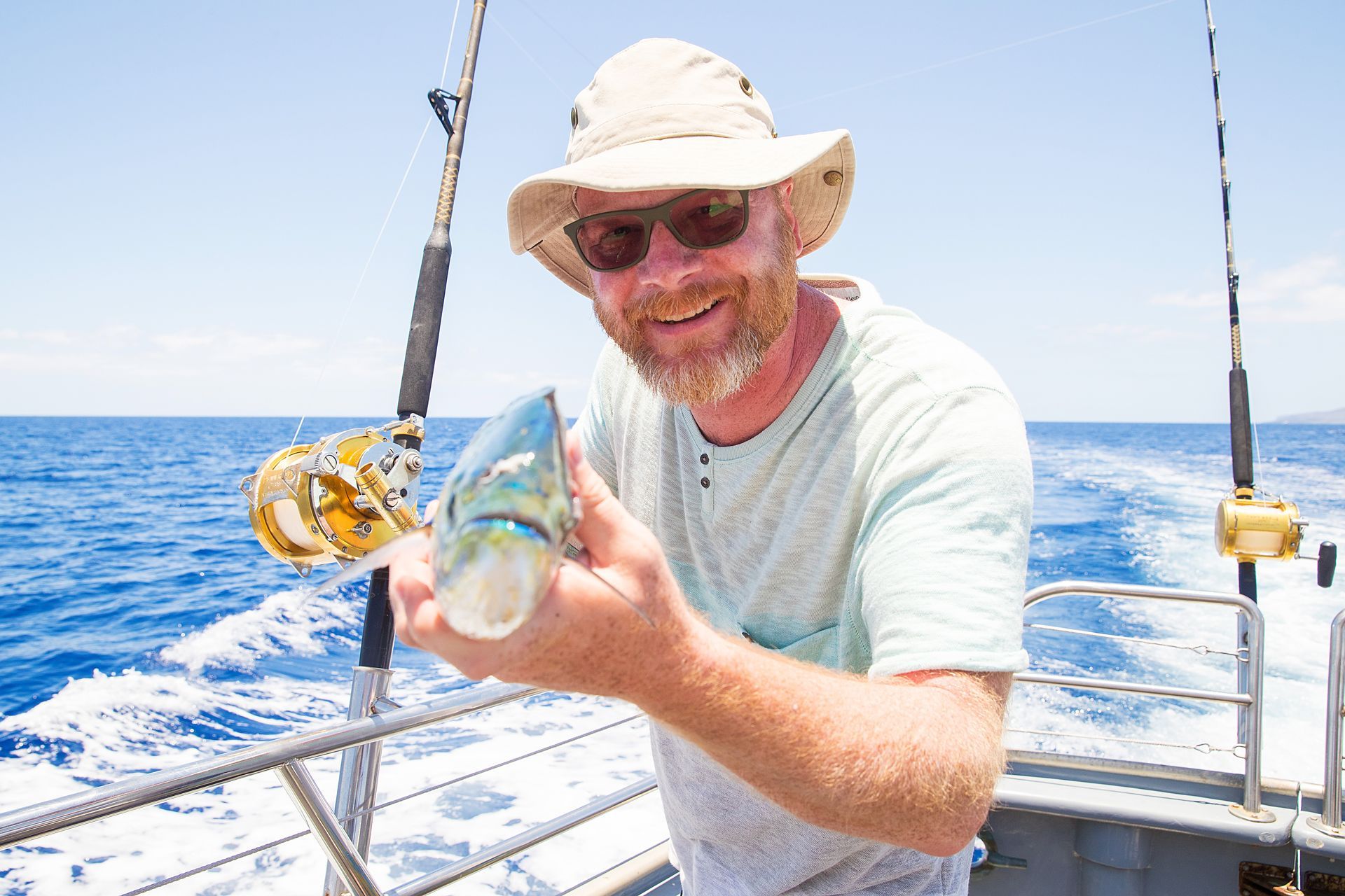 A man is holding a fish on a boat in the ocean.