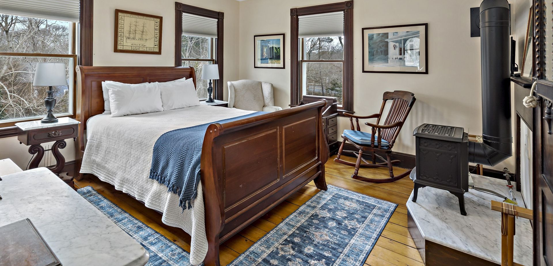 A bedroom with a bed , chair , fireplace and rug.