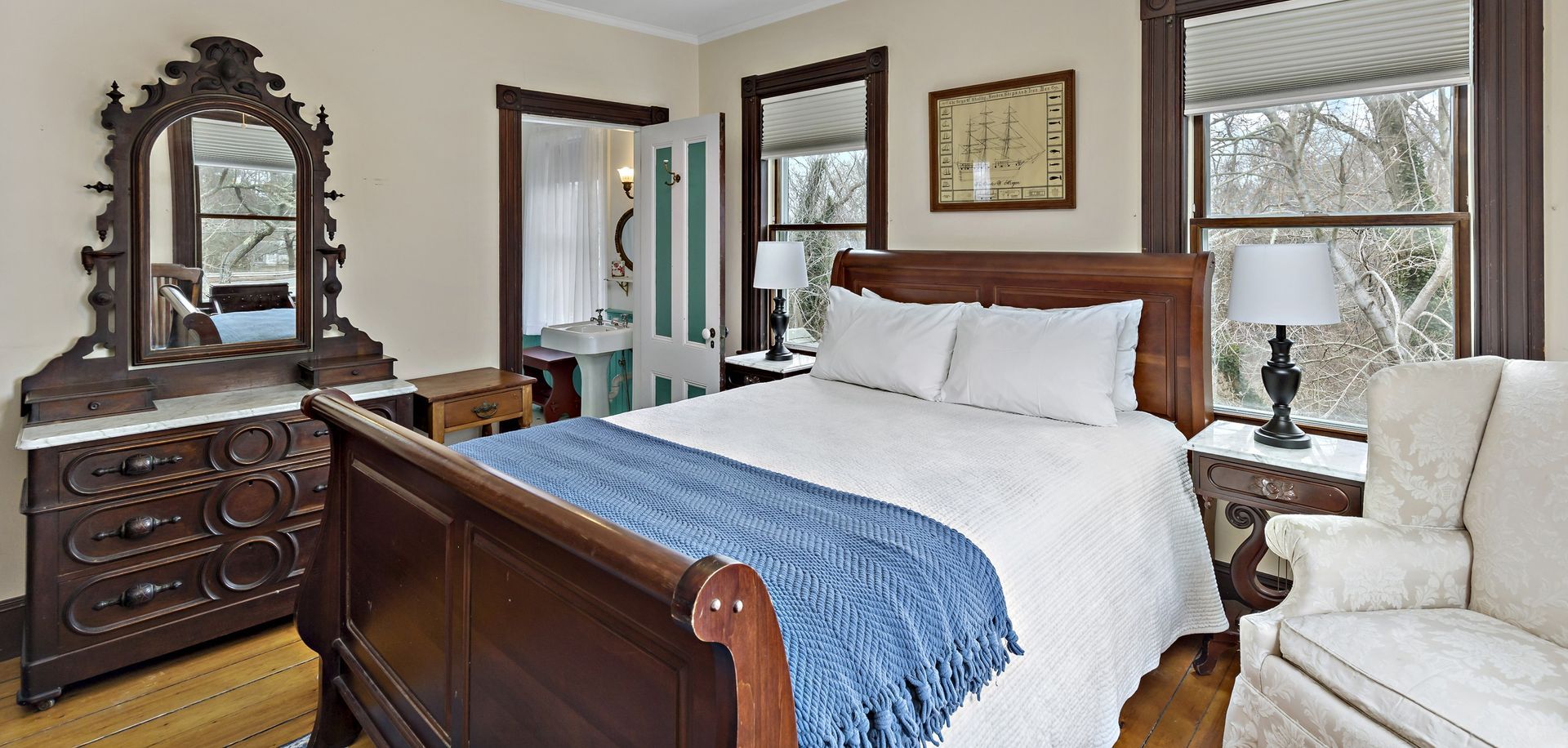 A bedroom with a bed , dresser , chair and mirror.