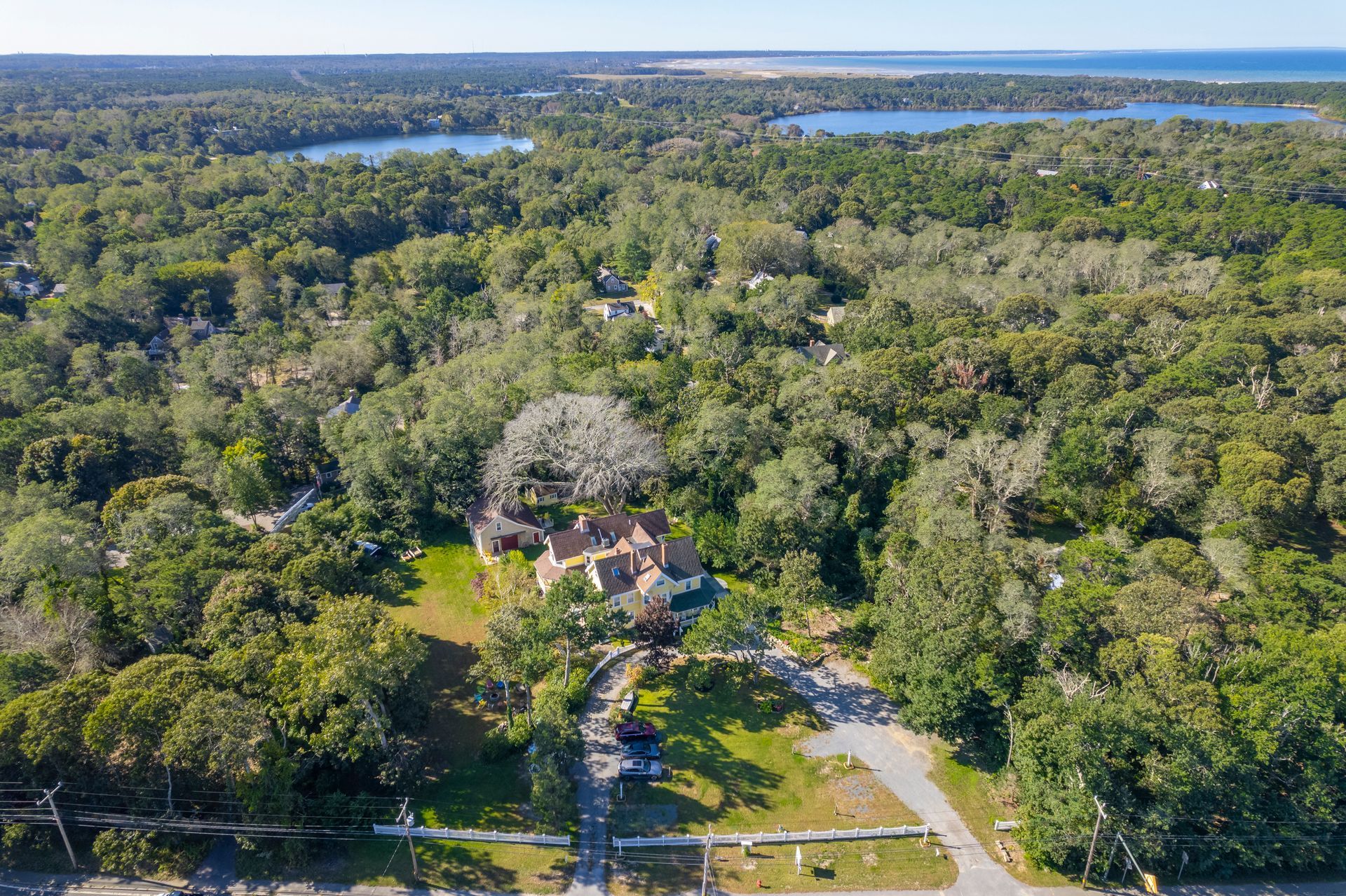 An aerial view of a house surrounded by trees and a lake.