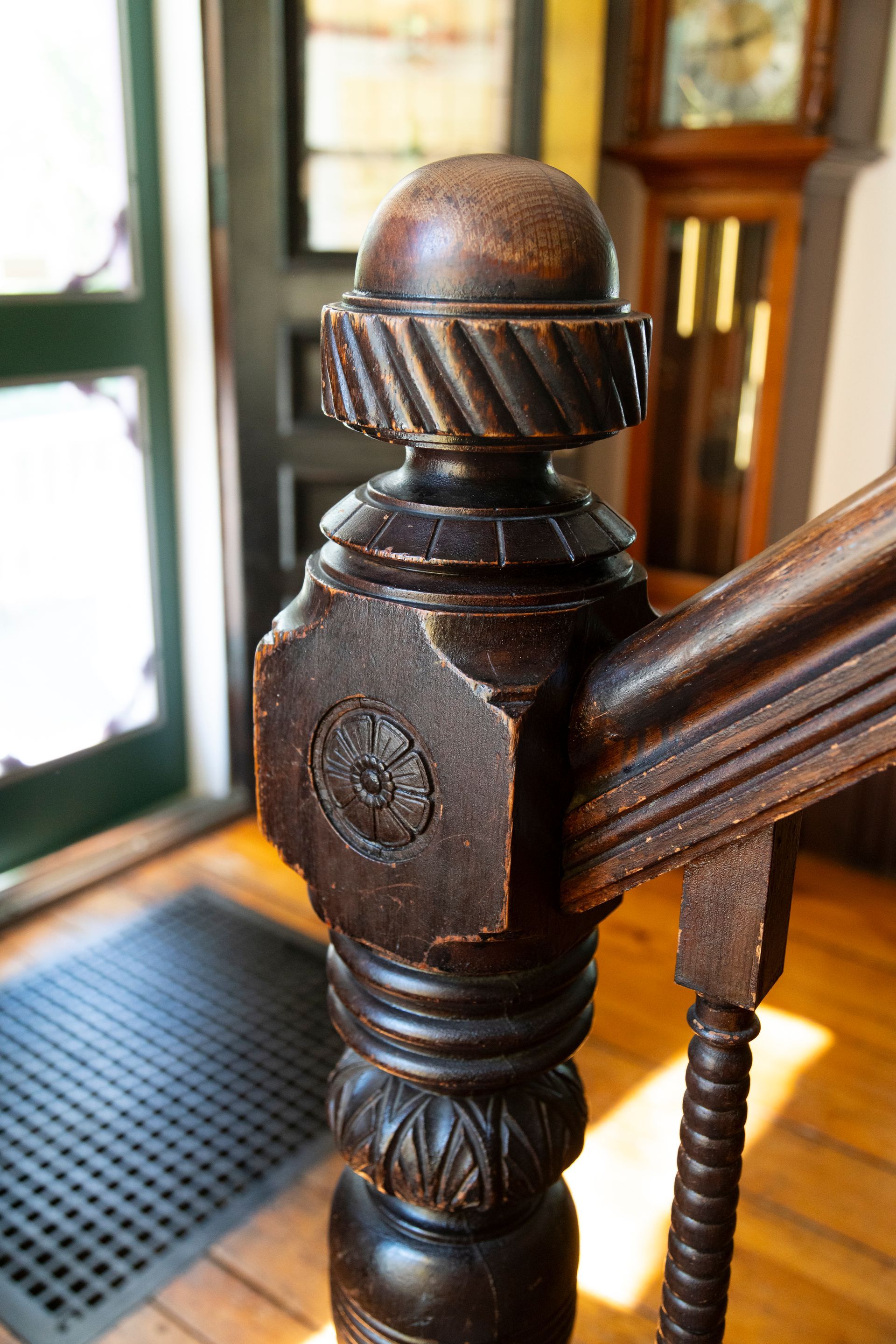 A close up of a wooden railing with a clock in the background.