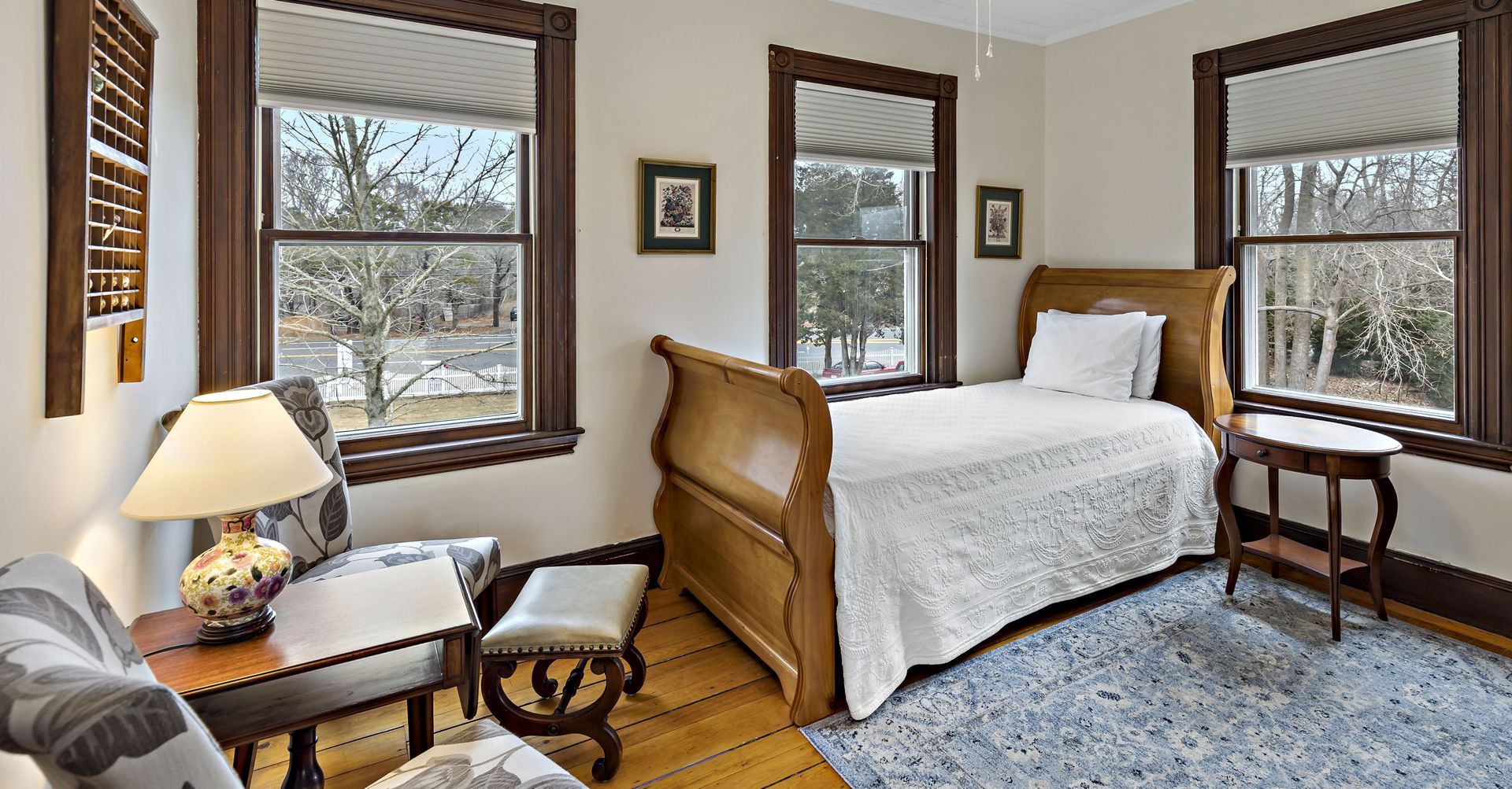 A bedroom with a sleigh bed , chair , table and lamp.