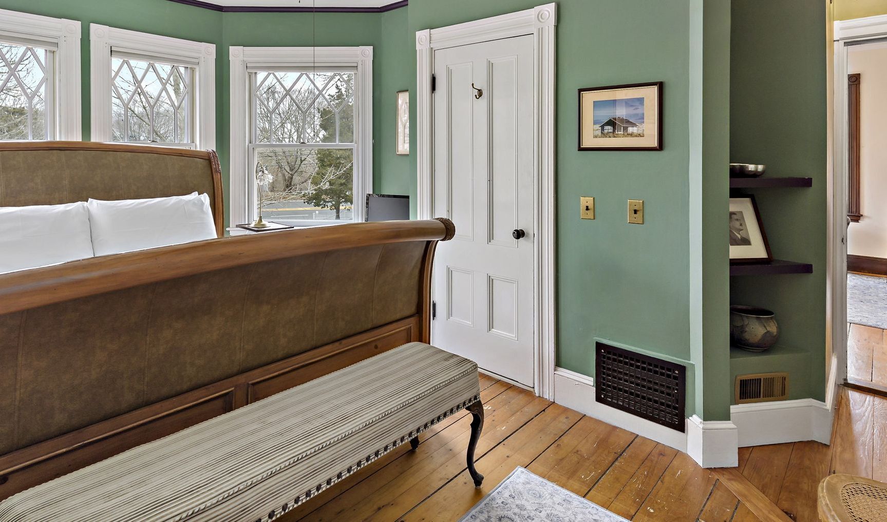A bedroom with green walls and a sleigh bed