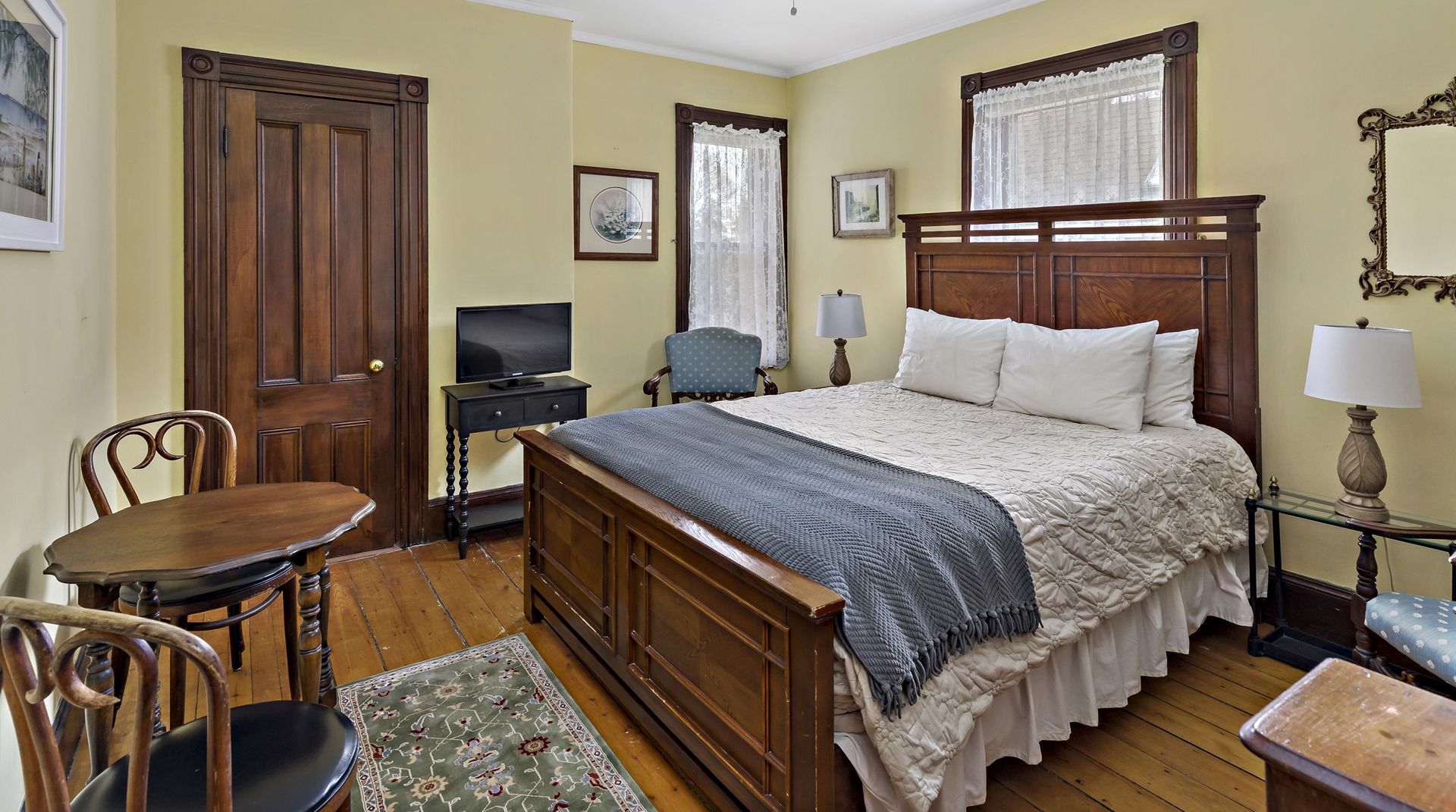 A bedroom with a large bed , a table , chairs and a television.