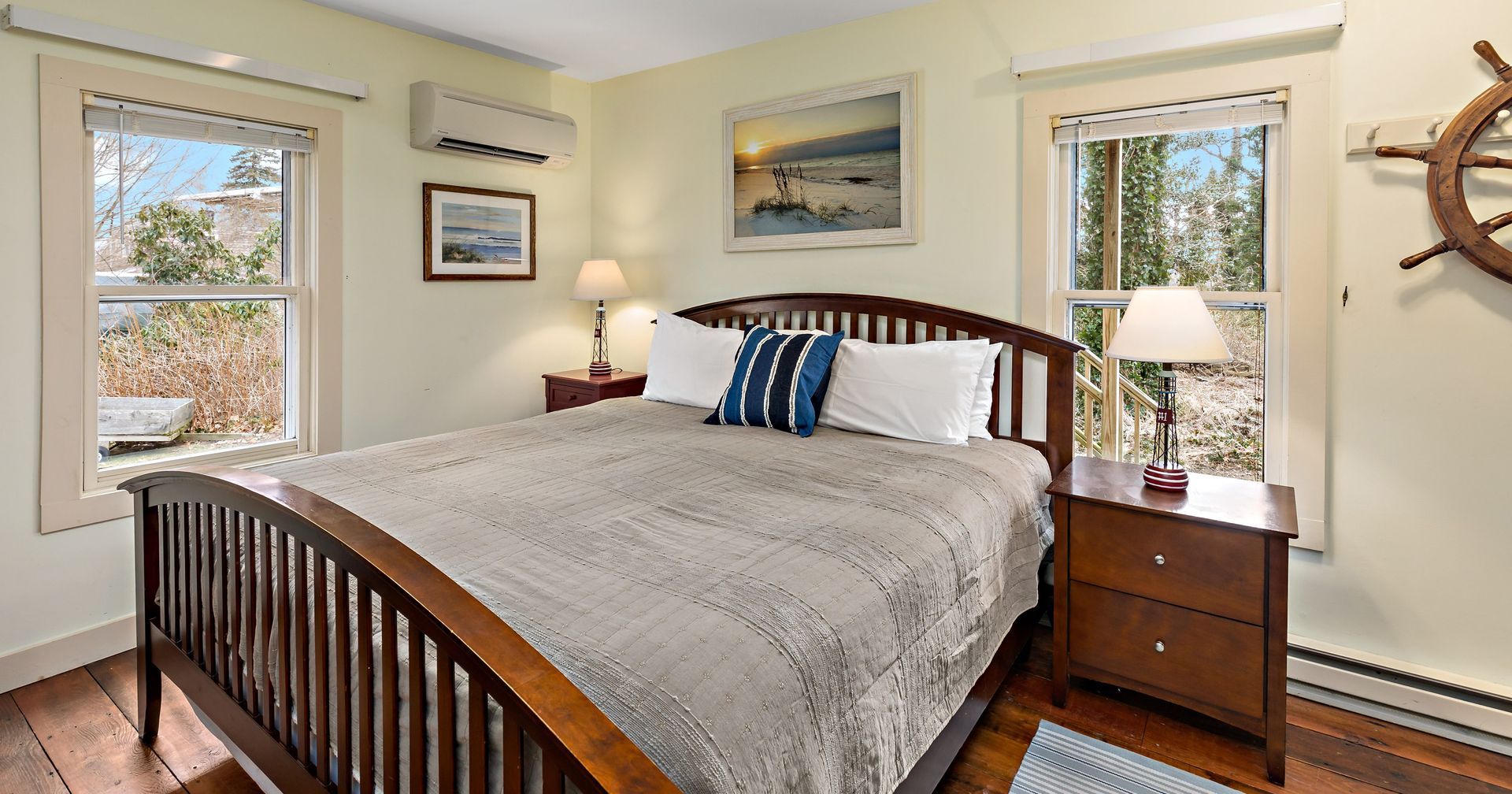 A bedroom with a bed , nightstand , lamp and a steering wheel on the wall.