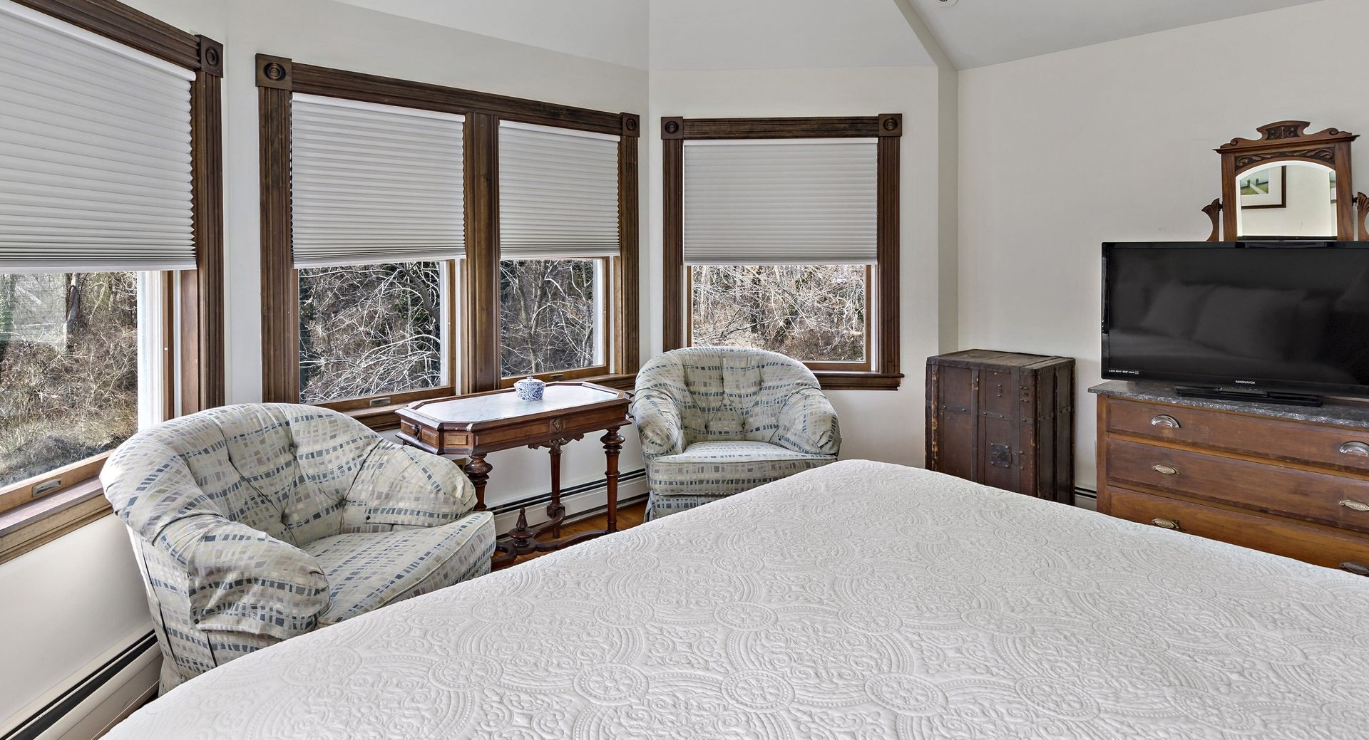 A bedroom with a bed , chairs , dresser and television.