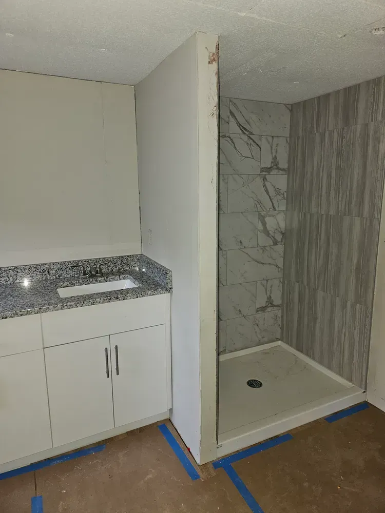 A bathroom with a sink and a walk in shower.