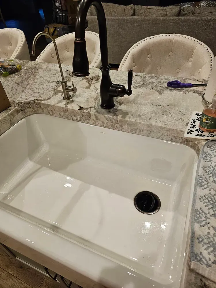 A white kitchen sink with a black faucet on a counter.