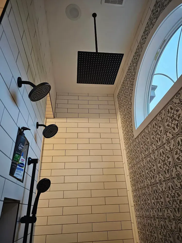 A bathroom with two shower heads and a window.