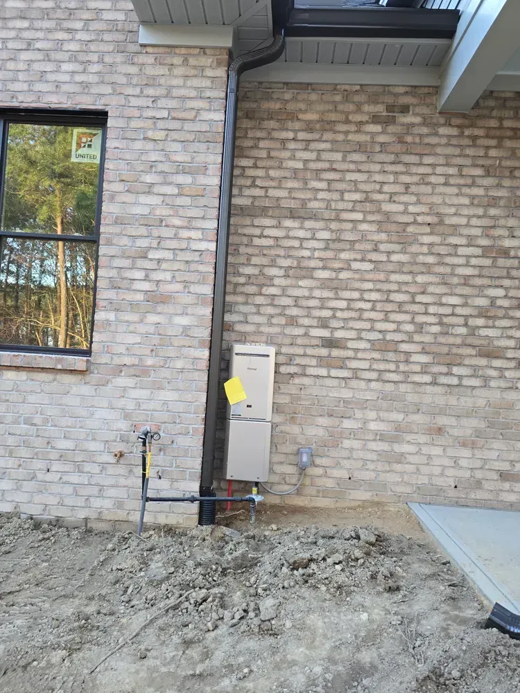 A brick building with a window and a drain pipe on the side of it.