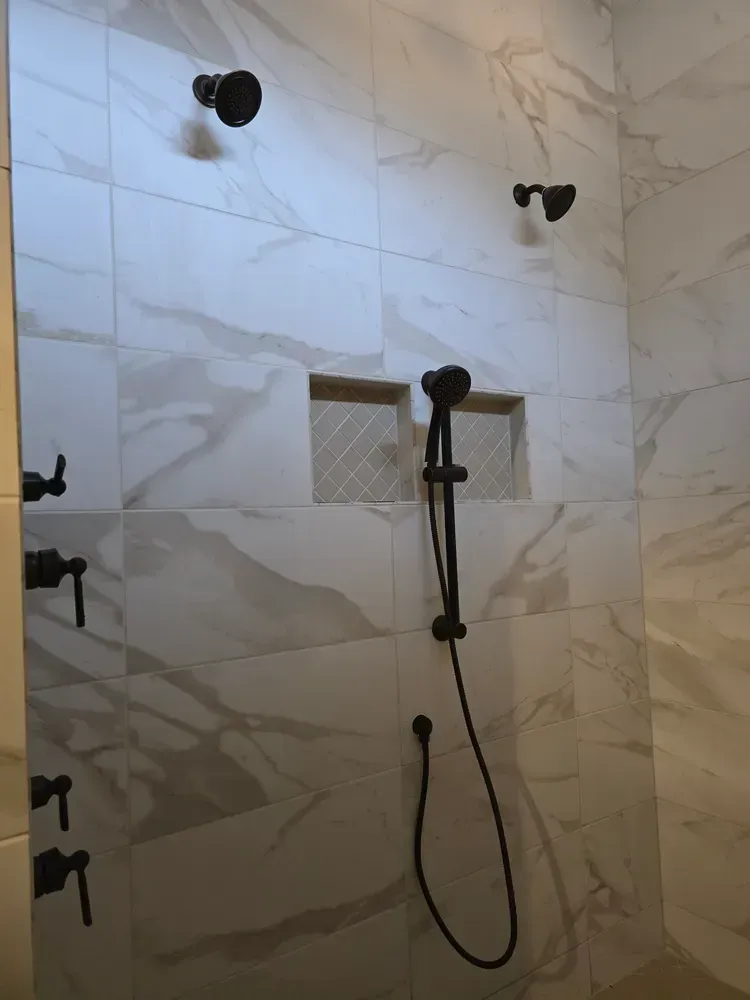 A shower with marble tiles and a black shower head