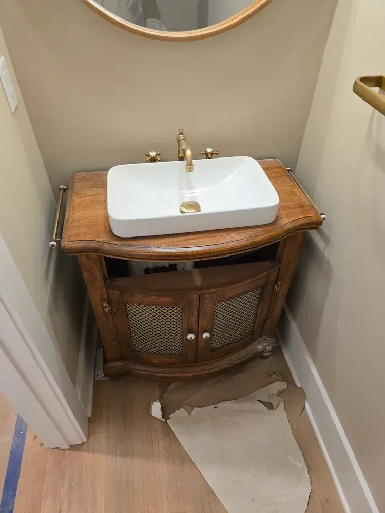 A bathroom sink is sitting on top of a wooden vanity.