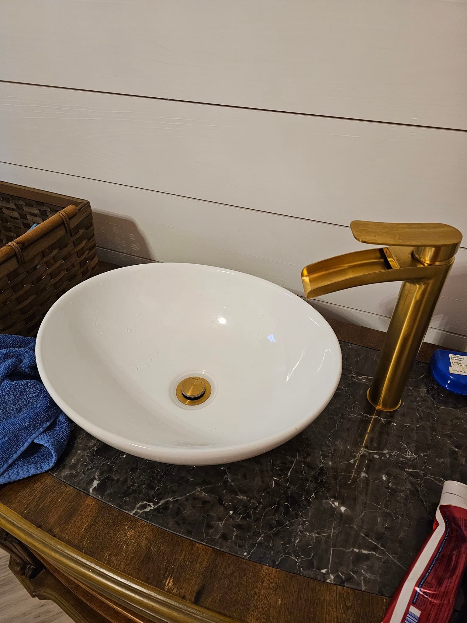 A white sink with a gold faucet is on a bathroom counter.